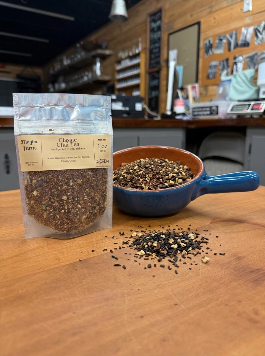 Classic Chai Tea in a 1 oz pouch beside a bowl of loose black tea and whole chai spices, hand packed at Mayim Farm in Opp, Alabama