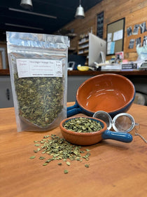 Moringa Orange Tea in a 1 oz pouch with a small dish of the loose moringa leaf blend and a tea ball strainer, hand-blended at Mayim Farm in Opp, Alabama