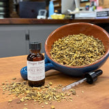 Poke Root liquid herbal extract in a 1 oz amber dropper bottle beside a bowl of dried cut poke root, extracted in small batches at Mayim Farm in Opp, Alabama