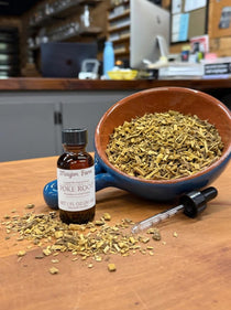 Poke Root liquid herbal extract in a 1 oz amber dropper bottle beside a bowl of dried cut poke root, extracted in small batches at Mayim Farm in Opp, Alabama